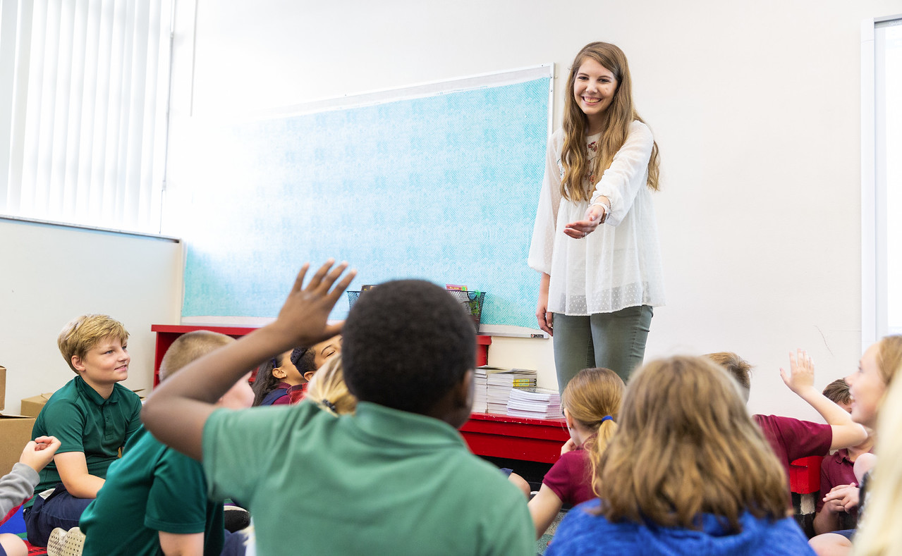 a teacher taking questions from students in a classroom