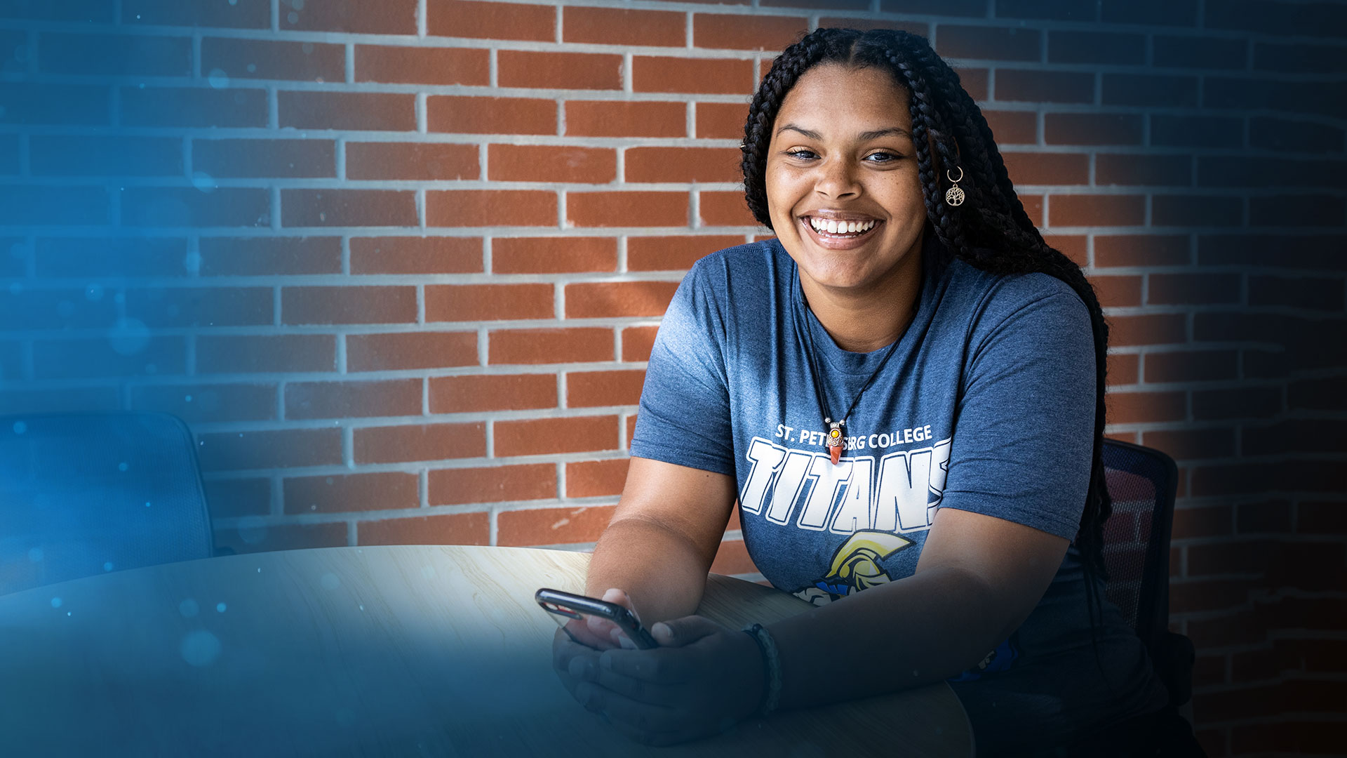 spc student smiling sitting at a table in front of brick wall