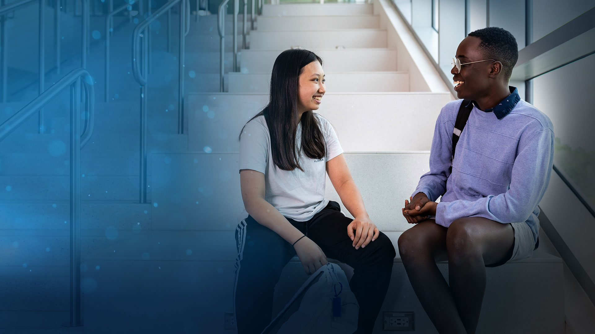 SPC students sitting on a staircase smiling at each other