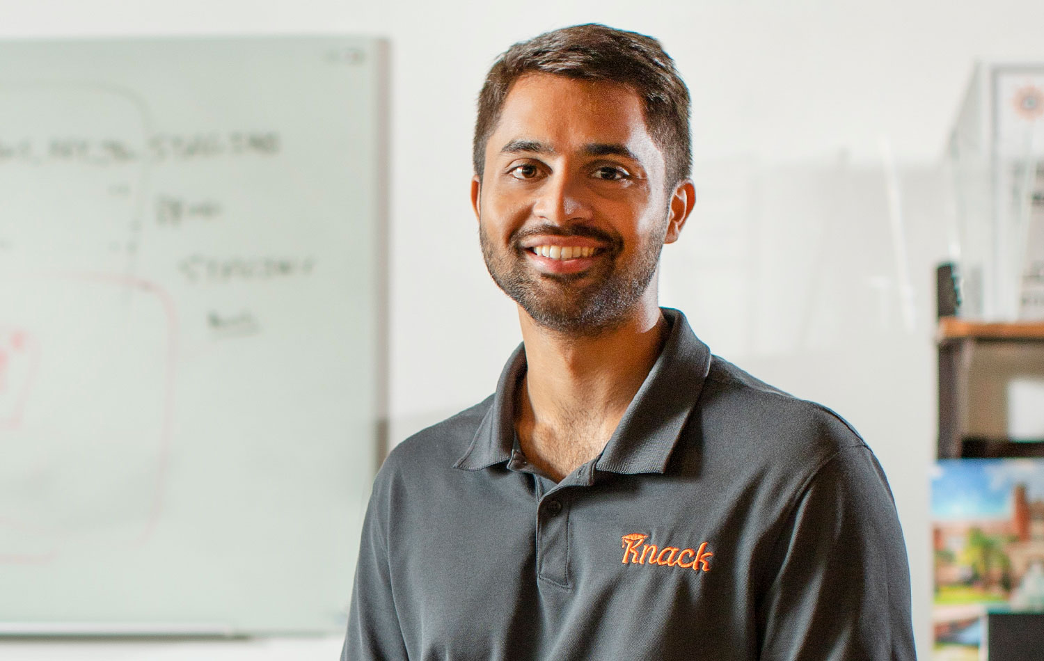 Samyr Qureshi posing for a photo wearing a gray Knack polo shirt