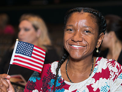 A female SPC student waving a small United States of America flag at an event.