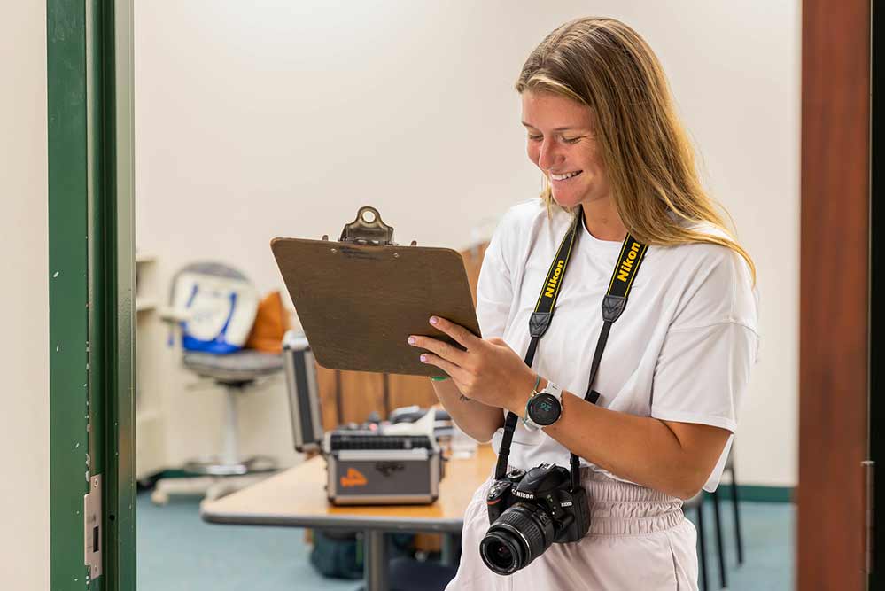 a female crime scene technology student taking notes and pictures