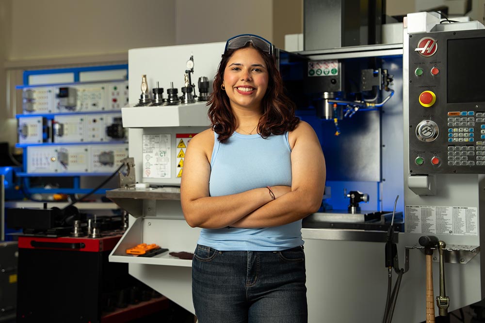 female student wearing safety goggles in front of manufacturing equipment