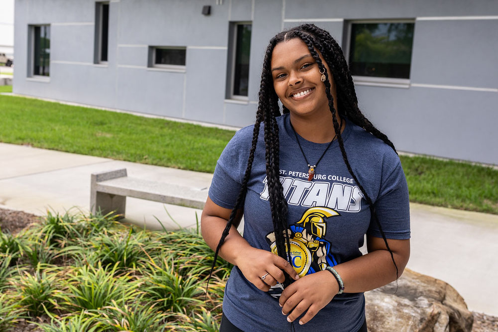female SPC student wearing a gray SPC t-shirt looking up and smiling