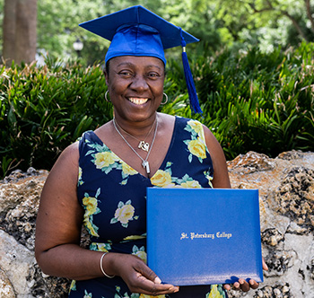 An SPC graduate posing with her cap and diploma.