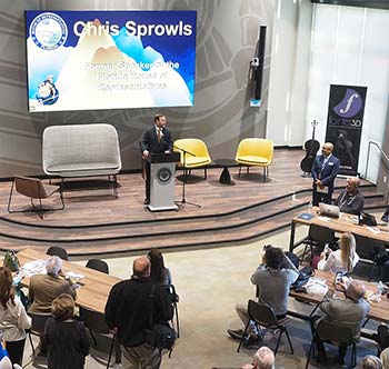 A man wearing a suit standing on stage at a podium, speaking at the Chris Sprowls Innovation Hub.