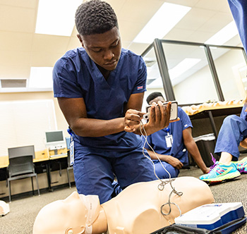 male student practicing CPR on a dummy