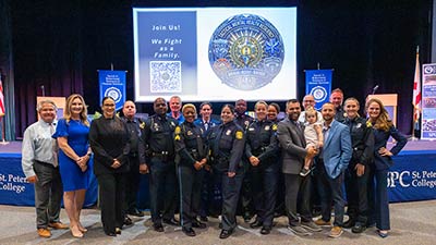 a group of first responders in uniform gather with supporters in front of a stage