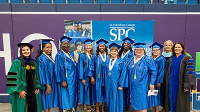 a group of teacher apprentices in blue caps and gowns at graduation