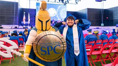 Titus the TItan Mascot and a graduate in blue cap and gown