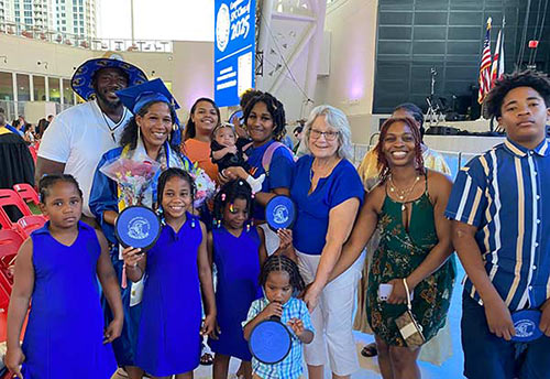 SPC graduate Melanie Williams posing in her blue cap and gown with her family members