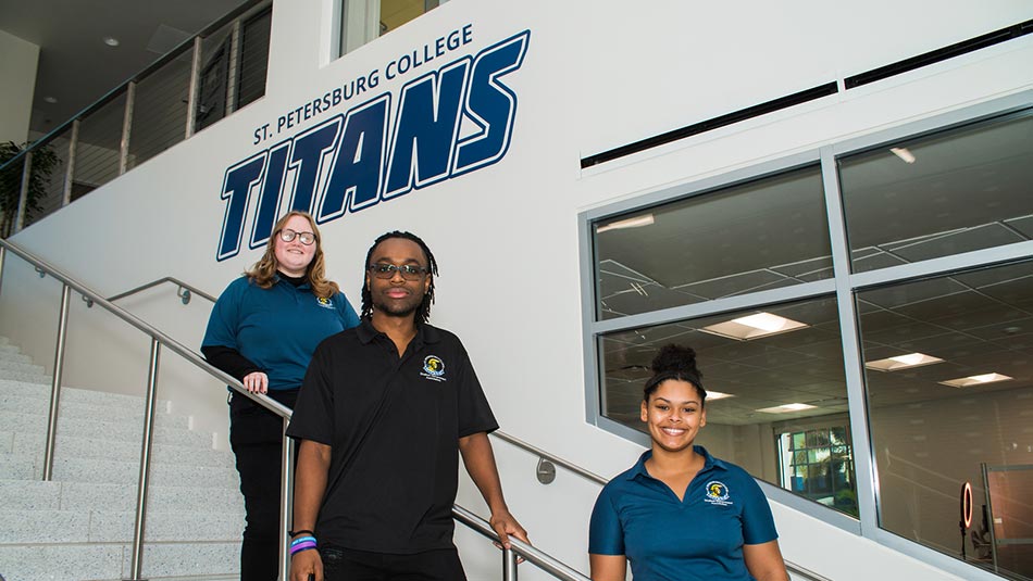 a female, male and female student in SPC polo shirts standing on staggered stairs