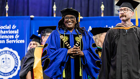 SPC President, Dr. Tonjua Williams, posing in her cap and gown at a graduation ceremony