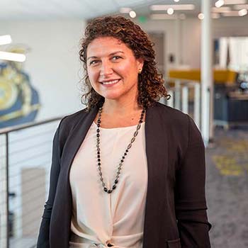 A portrait of Luisa Shamas wearing a brown blazer and white blouse.