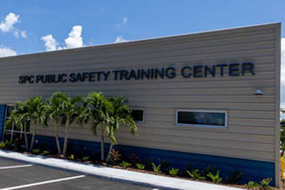 Public Safety Training Center building from an angle, under blue skies and behind a row of palm trees.
