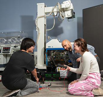 male and female SPC collegiate high school students repairing biomedical technology equipment with professor Brian Bell at the Tarpon Springs Campus