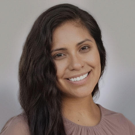 Portrait of Clara Saenz wearing a beig top smiling at the camera
