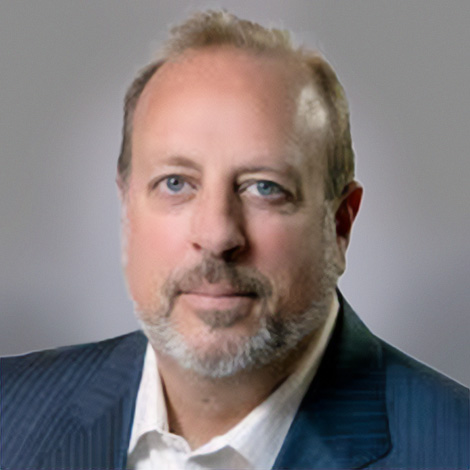 Greg Buschman wearing a grey suit with white shirt smiling at the camera