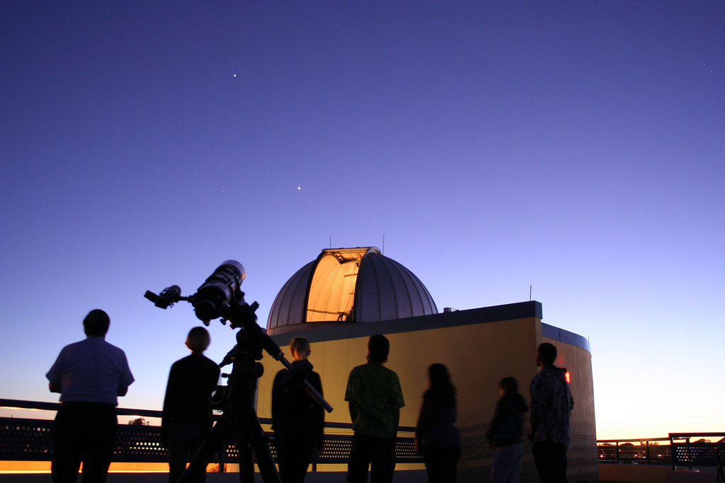 silhouettes of students gathered around the SPC Planetarium at dusk