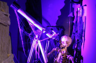 human skeleton looking through a telescope