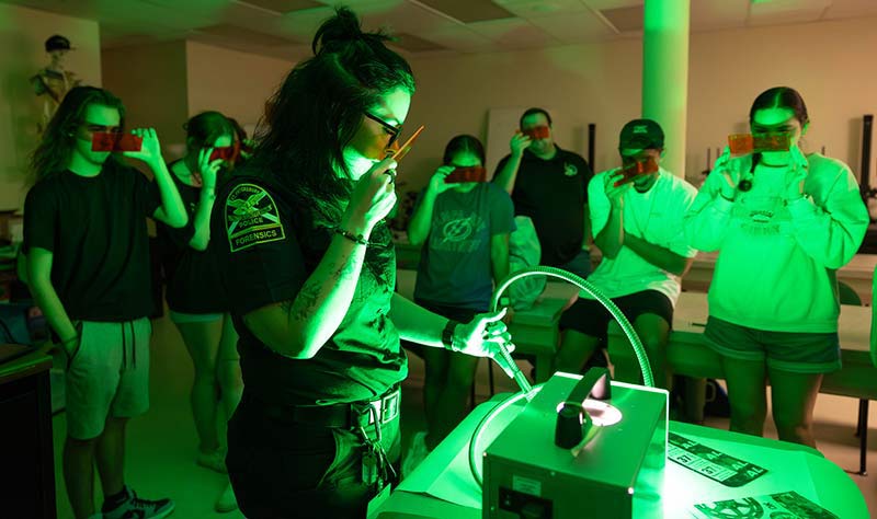 group of students watching a police officer run fingerprints