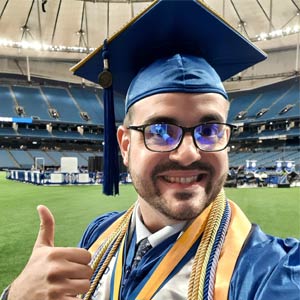 photo of Eleftherios Venieris wearing full graduation gown giving thumbs up at the camera