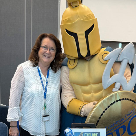 portrait of Lynn Ernst standing with Titus the yellow Titan mascot