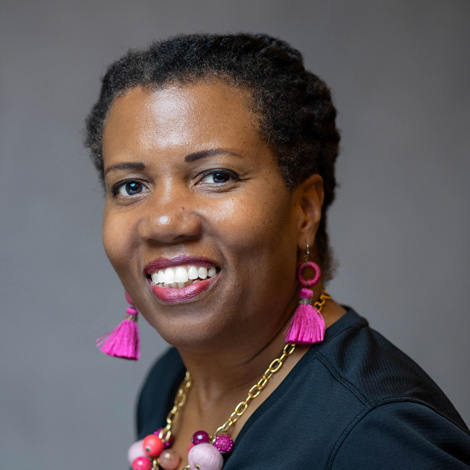 portrait of Stephanie Henningson wearing pink earrings and necklance in a black suit jacket