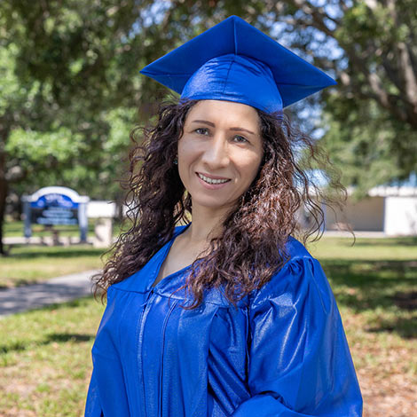portrait of Zoilita Andrade wearing her blue graduation cap and gown