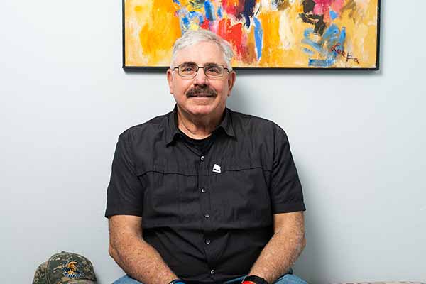 An SPC student seated in front of an abstract painting.