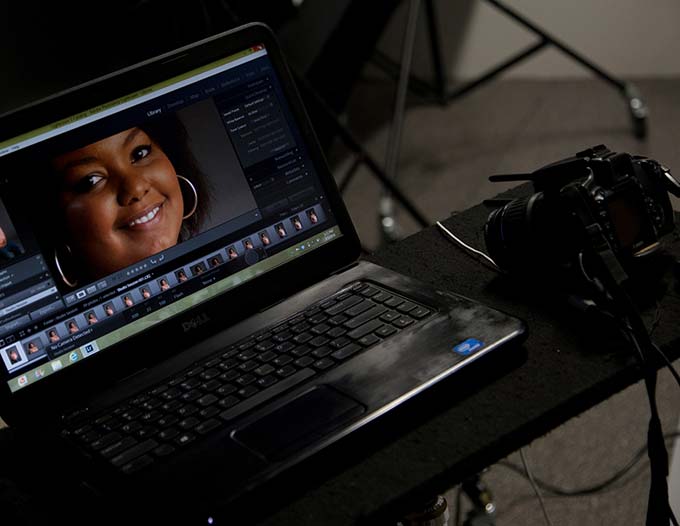 A laptop showing digital imaging software sitting on a table beside a digital camera.