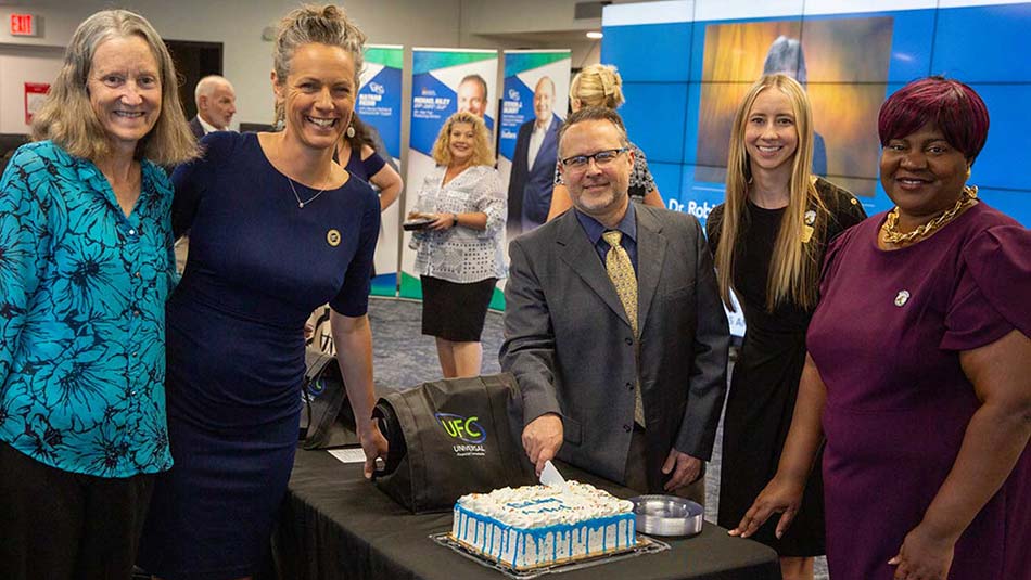 SPC employees smiling and cutting a cake
