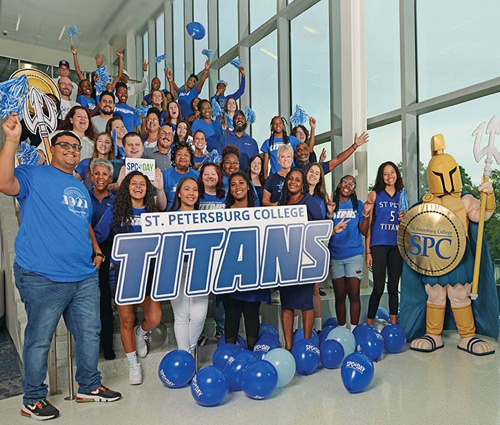 a group of students on campus holding up a Saint Petersburg College Titans banner