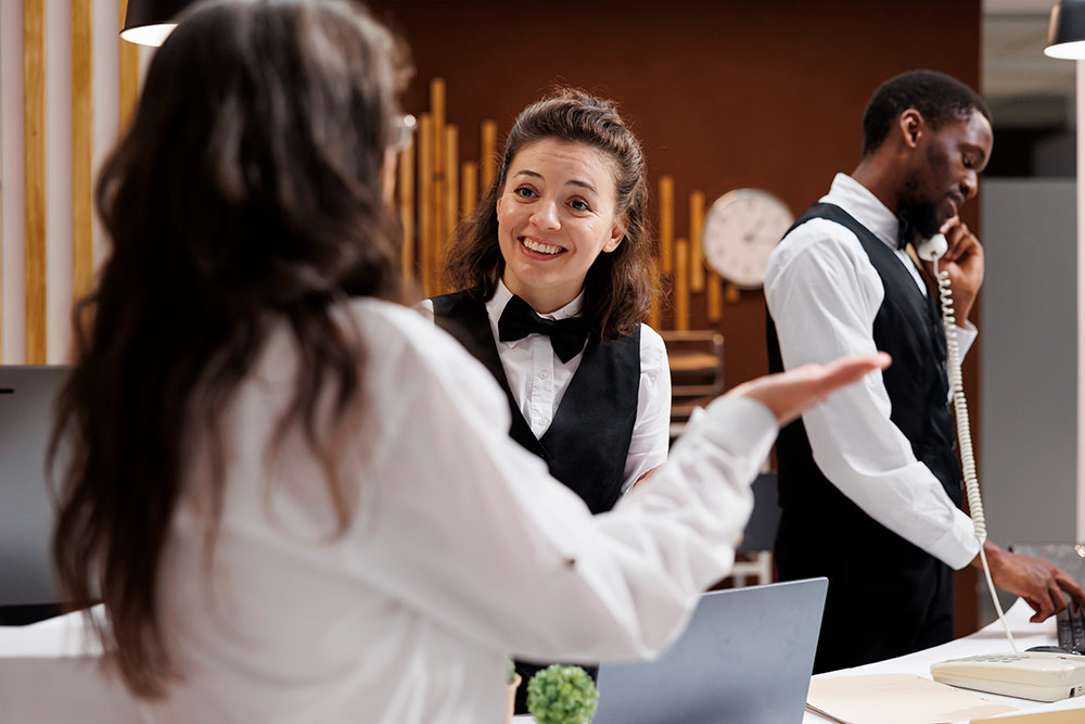 male and female hospitality managers greeting guests at the front desk