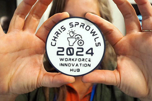 person holding a plastic badge created with a 3D printer  with the words Chris Sprowls Workforce Innovation Hub