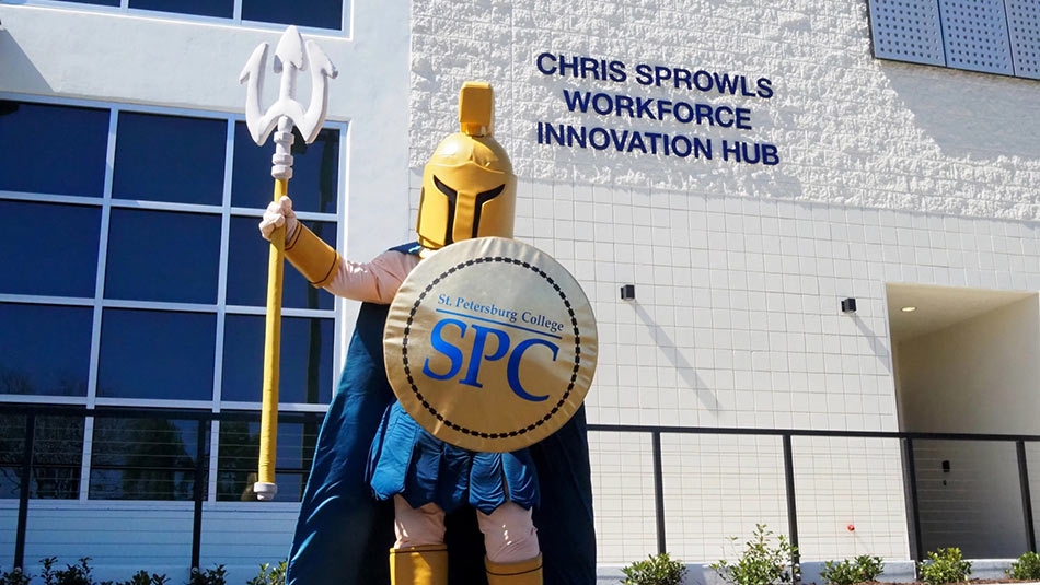 Titus the Titan mascot holding a spear standing in front of the Chris Sprowls Workforce Innovation Hub at the Tarpon Springs Campus