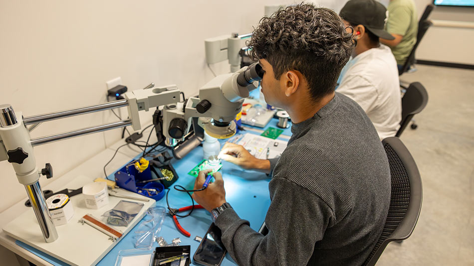 two SPC students looking through a microscope to make precise soldering