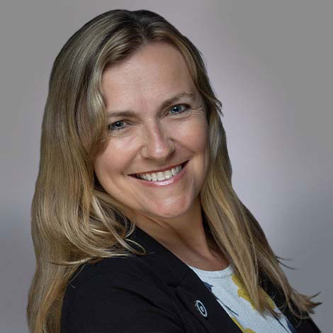 photo of a smiling blonde woman looking sideways wearing a black suit