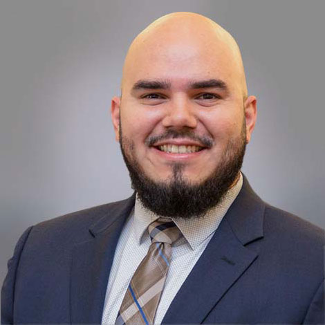 photo of a smiling bald bearded man wearing a grey suit