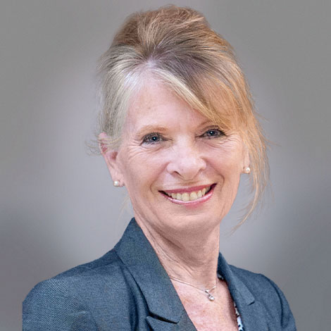 photo of a smiling blonde woman looking sideways wearing a grey suit