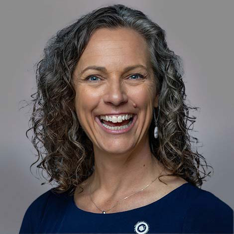 photo of a smiling woman with long wavy hair wearing a grey suit