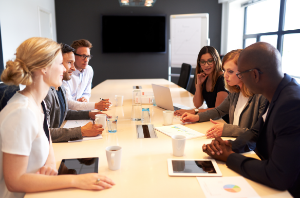 a group of people meeting at a table inb a corporate conference room