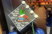 SPC graduate decorated cap with pompoms and text