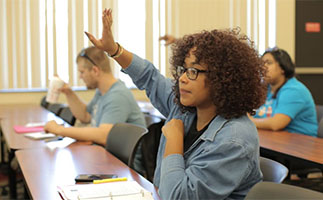 students in a classroom and a woman with her hand raised