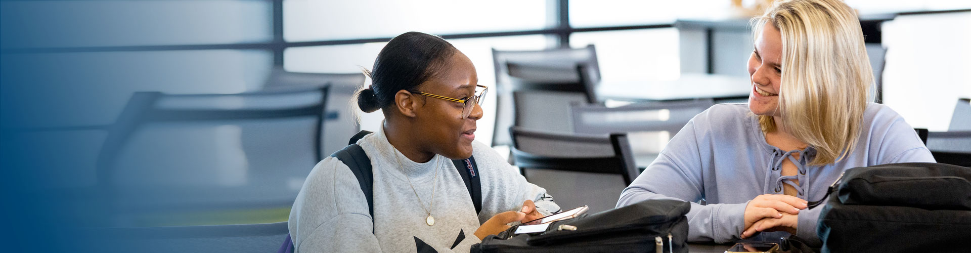 image of a female advisor in a blue shirt assisting a female student in a greay sweatshirt